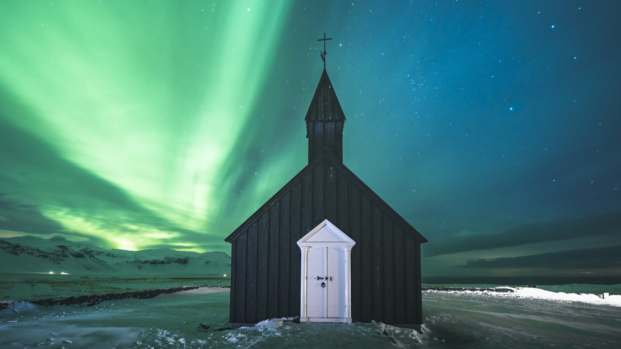 یک کلیسای سیاه زیر نورهای شمالی با رگه هایی از نور سبز که در سراسر آسمان می رقصند.